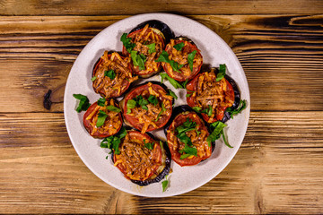 Baked eggplants with tomatoes and cheese in a ceramic plate. Top view