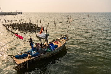 Fishing boats floating in the golden sea at sunset.