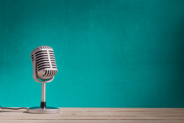 Retro microphone on wooden table with green wall background