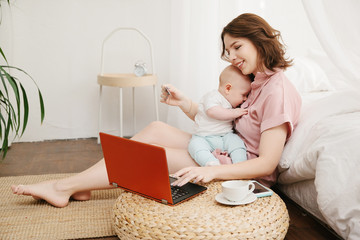 portrait of mother and little son doing online shopping with credit card, using laptop.