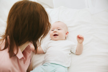Young mother and baby lying on the bed at home