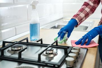 young woman cleaning in rubber gloves and sponge in the kitchen at home