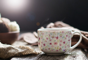 Cup of tea, coffee on an old wooden table against the background of knitting tools.