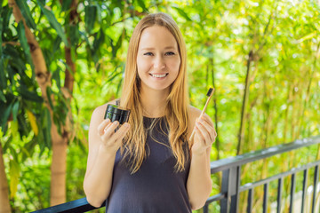 Young woman brush teeth using Activated charcoal powder for brushing and whitening teeth. Bamboo...