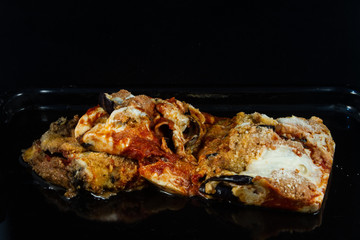 very close up of portion of Italian parmigiana that thaws quickly on a black background