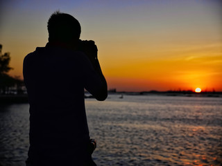 The photographer is shooting the sunset in the sea