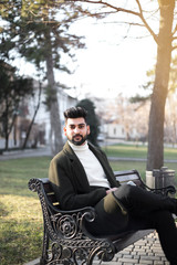 Obraz premium Young Indian businessman seating on the bench in park with smartphone.