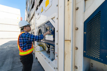 Fototapeta premium Young man Reefer technician is monitoring reefer container at the container storage