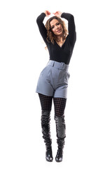 Carefree happy young trendy beautiful woman having fun dancing with hands raised above head. Full body isolated on white background.