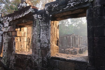 amazing sun, sunset shining through old windows in temple ruins of unesco site angkor wat, cambodia