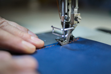A man sews from leather on a sewing machine. Hands and sewing. Production of leather goods using a sewing machine