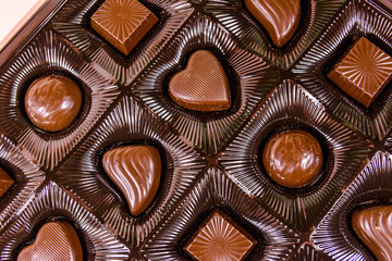 Heap of chocolate candies in a brown box. Top view