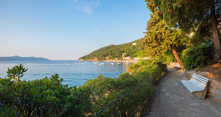 idyllic walkway along seaside of Moscenicka Draga, with resting bench, croatian landscape