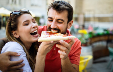 Happy couple eating pizza while traveling on vacation