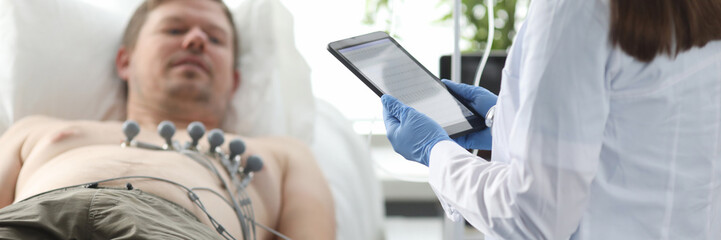 Focus on smart woman practitioner standing in modern clinic office and looking at high-tech tablet...