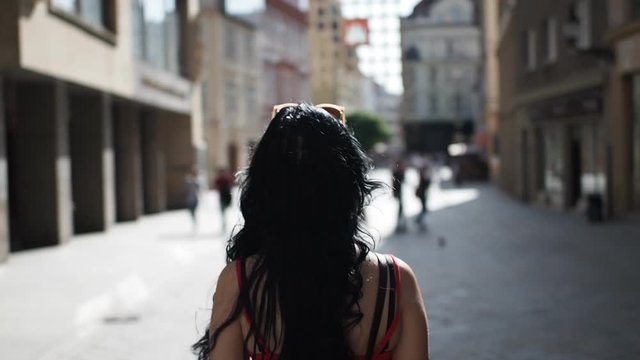 Young brunette woman is walking through the street, looking around and enjoying free time in historical part of Bratislava city in SLOW MOTION HD VIDEO. Half speed, rear view.