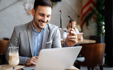 Happy confident businessman working, using laptop in office