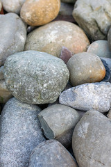 The surface of the beach on the ocean is covered with large polished round stones of gray color of different sizes. Natural background of a big rocks or pebbles on the seashore close-up.