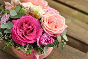 Beautiful round pink box with floral composition with roses of different color. Flowers lush bouquet picture close up view. Holiday, birthday, florist shop business or beauty concept. Romantic flower