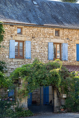 Facade of an old stone house with wooden shutters in Carlux. Dordogne valley, Aquitaine,  France