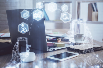 Computer on desktop in office with technology theme hologram. Multi exposure. Tech concept.