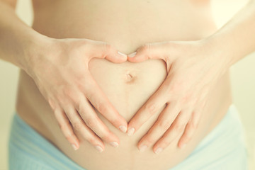 Pregnant woman making heart shape with her hands