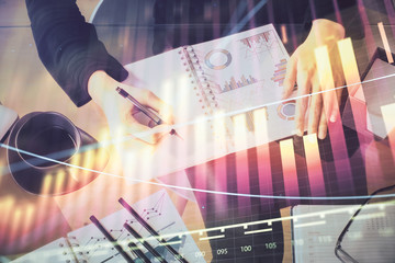 Multi exposure of hands making notes with forex chart huds. Stock market concept.