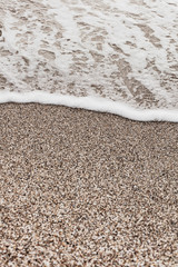 Different texture on the beach - water and sand, stones and pebbles, waves and splashes.