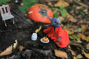 Grey handmade mouse in the red coat has a breakfast