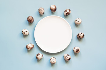 Easter eggs and white plate on blue background. Creative minimal pastel color holiday composition