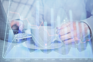 Double exposure of graph with man typing on computer in office on background. Concept of hard work.