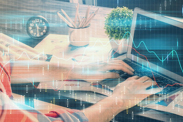 Double exposure of stock graph with businessman typing on computer in office on background. Concept...