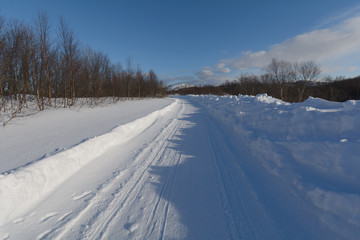 Obraz premium The dirt road is covered with ice and snow .Clear blue sky.
