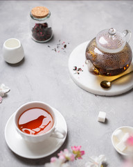 Fragrant tea in a cup with a reflection of a bird and teapot on gray background. Spring tea party. Cafe, reastaurant menu, poster, greeting card. Close up