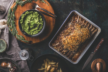Tasty roasted lamb ribs with crust and mashed green peas with mint and  baked potatoes on dark...