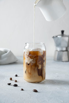 Iced Latte Coffee In Glass With Pouring Milk.Close Up. Vertical.