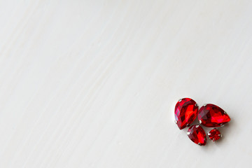 Red stones crystals beads on a white wooden background in the corner