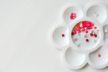 a set of beads and sequins in a container in the form of a flower