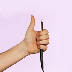Hand holding soldering iron thumbs up on purple background