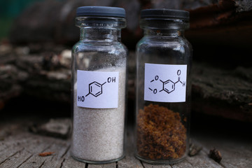 Two organic, chemical, crystalline substances, gray hydroquinone, brown aromatic aldehyde, in glass...