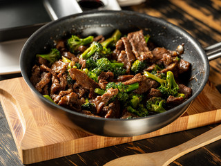 Beef meat and broccoli vegetable cooking in pan close up, selective focus. Traditional food recipe. - 323620411