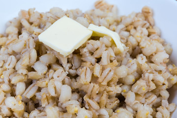 Pearl barley porridge with butter close-up in selective focus