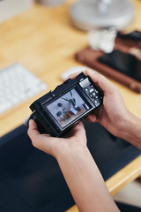 Close-up image of photographer designer checking digital camera with photos of interior design