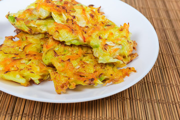 Savory cabbage pancakes on dish on bamboo table mat closeup