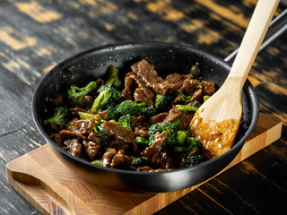 Beef meat and broccoli vegetable cooking in pan close up, selective focus. Traditional food recipe.