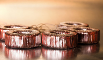 Close-up round transformer wrapped in wire lie on the table on top of each other. The concept of...