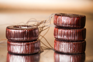 Close-up round transformer wrapped in wire lie on the table on top of each other. The concept of...
