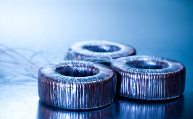Close-up round transformer wrapped in wire lie on the table on top of each other. The concept of...