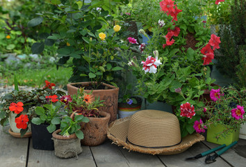 Garden patio with straw hat, petunia and pansy flowers in flowerpots.