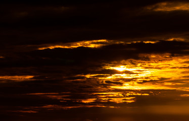 Beautiful sunset sky. Golden sunset sky with beautiful pattern of clouds. Orange, yellow, and dark clouds in the evening. Freedom and calm background. Beauty in nature. Powerful and spiritual scene.